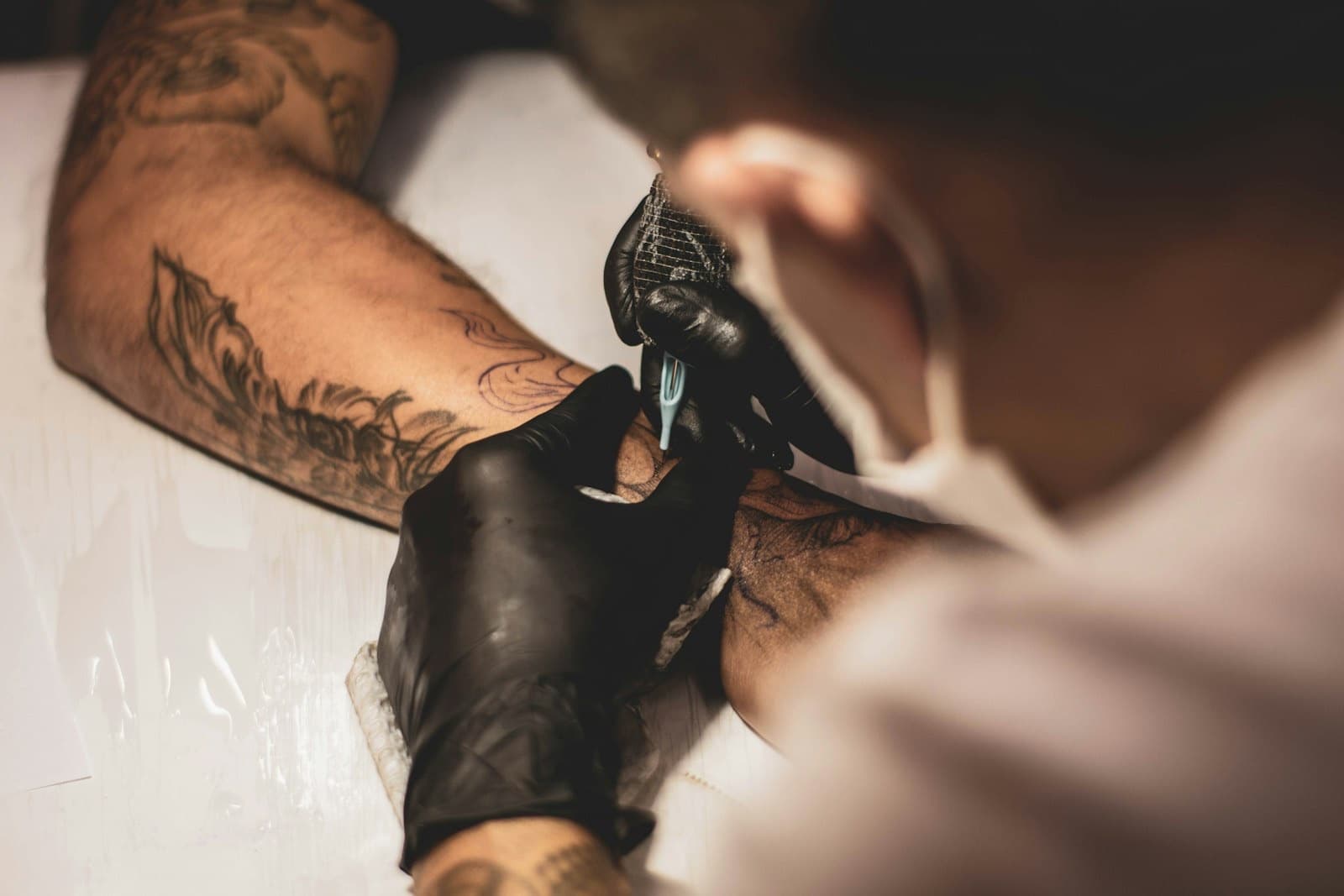 Tatuador de luvas pretas a tatuar um antebraço